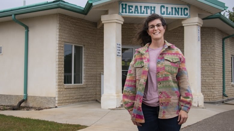 A woman stands in front of a health clinic.