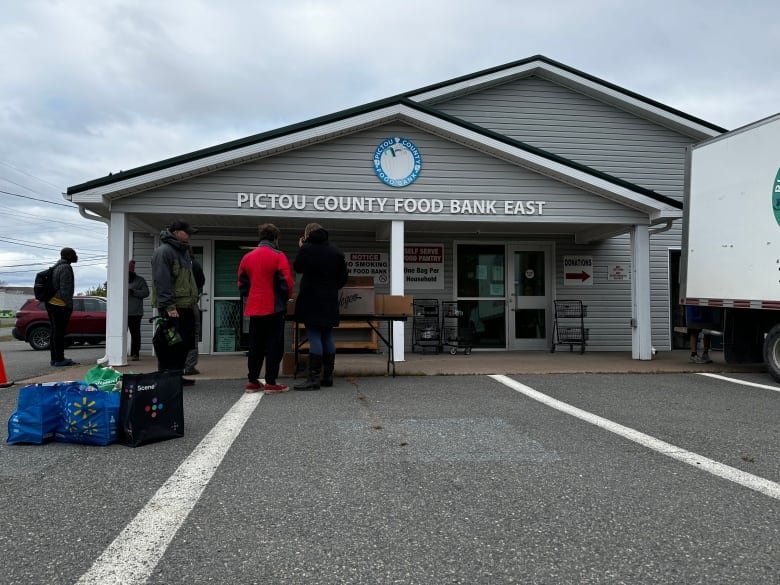 Four people are standing outside of the food bank.