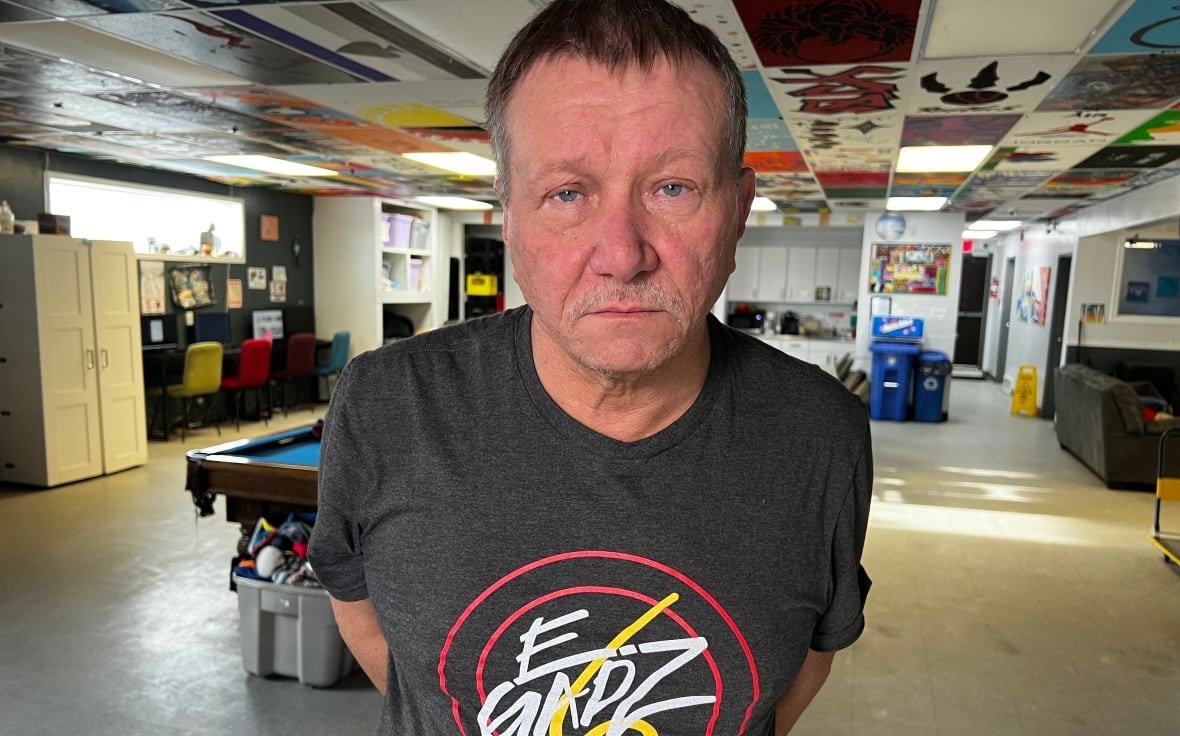 A man stands and poses for a photograph inside a rec centre.