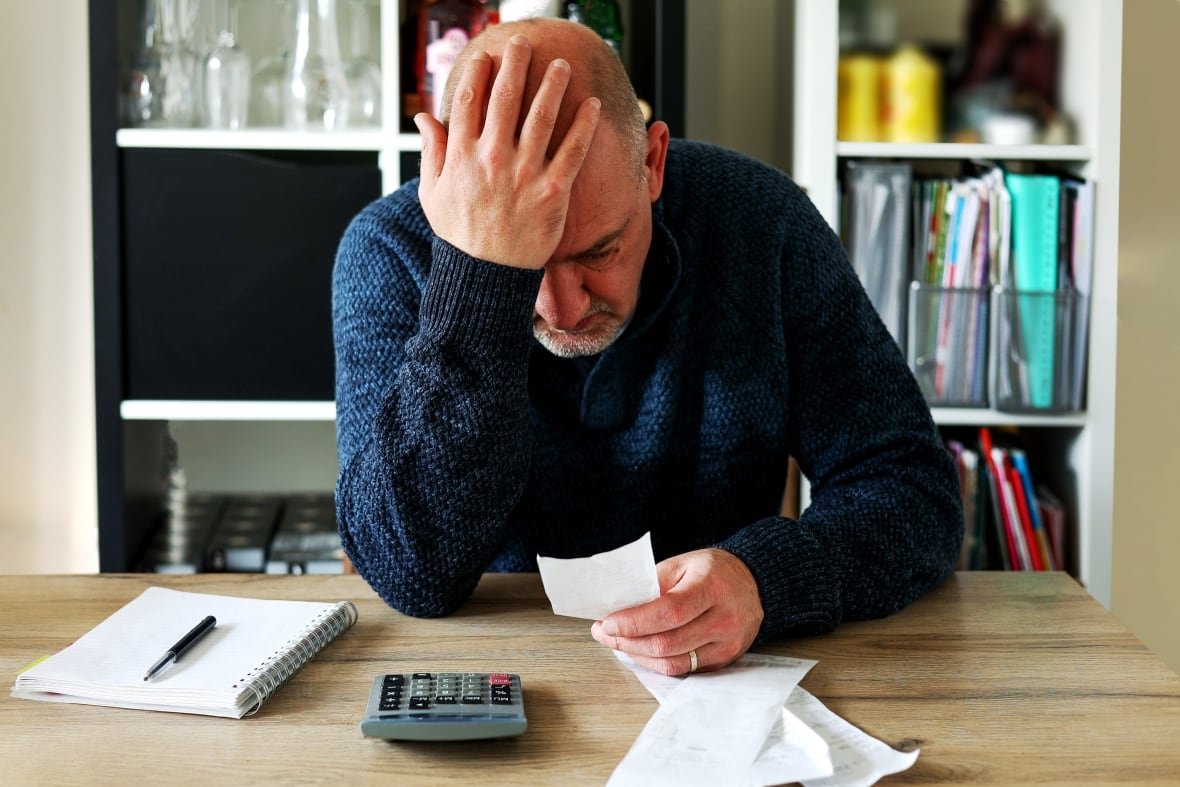 Man stressed with bills and calculator.