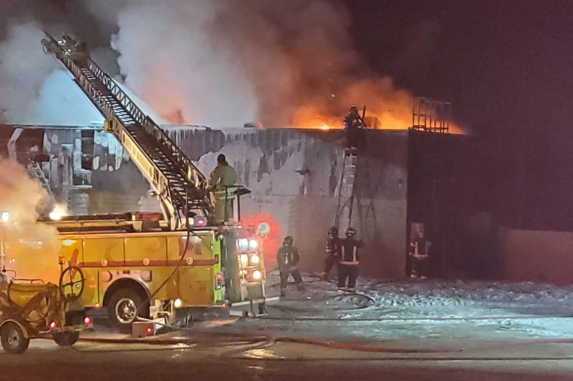 A group of firefighters try to put out flames at a burning building.