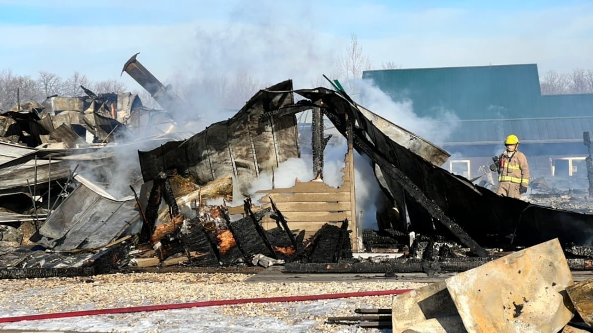 A firefighter hoses down a smoldering building after a fire.