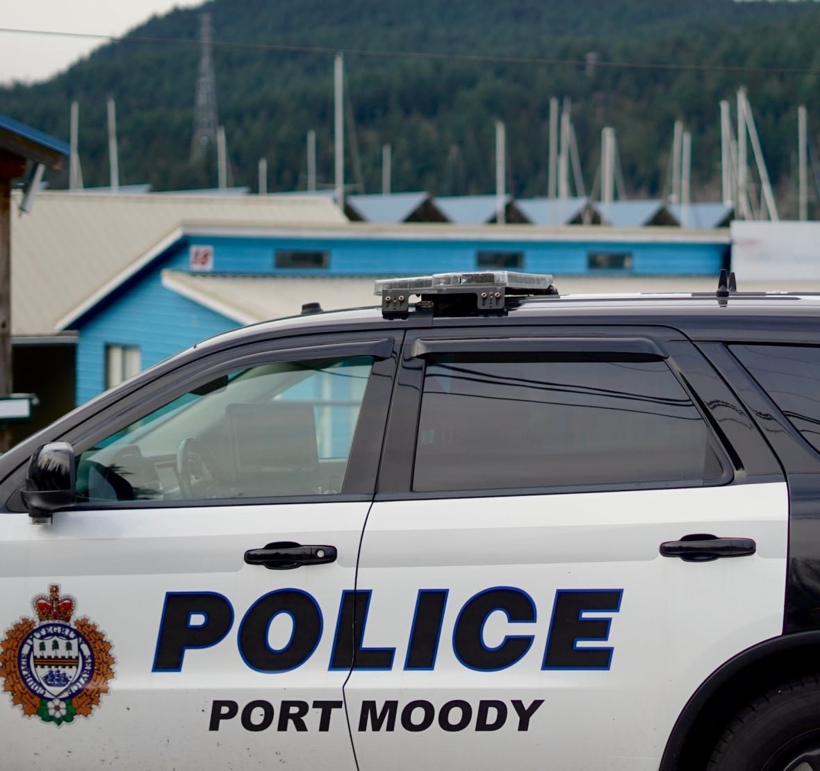 A police car is seen near pointed marina roofs and sail masts.