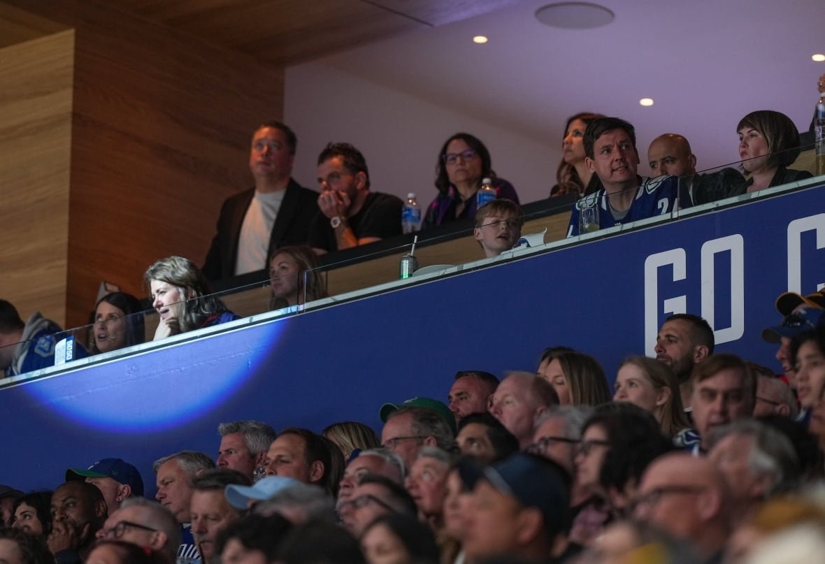 Politicians and others in a hockey arena luxury box.