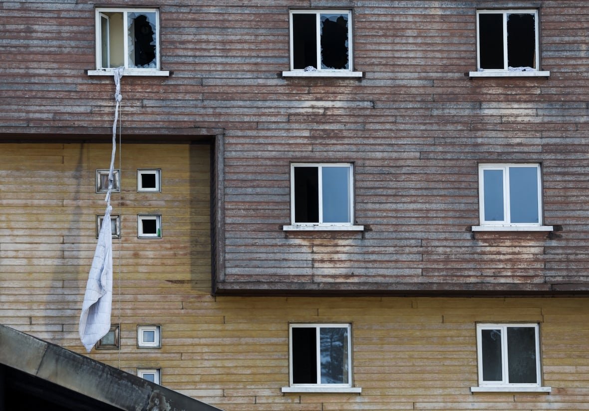 Tied bedsheets hang from a broken window.