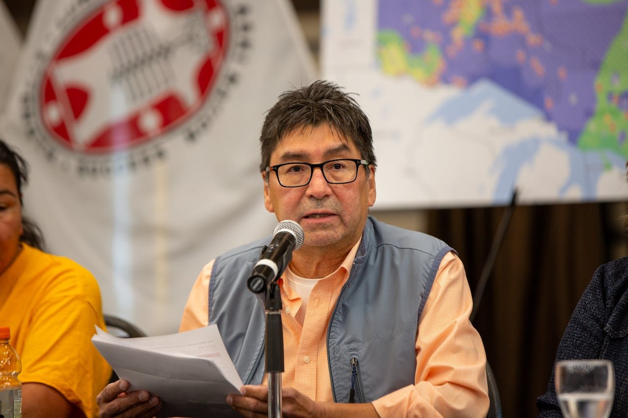 default-203 A person is seen speaking at a table with flags behind them.