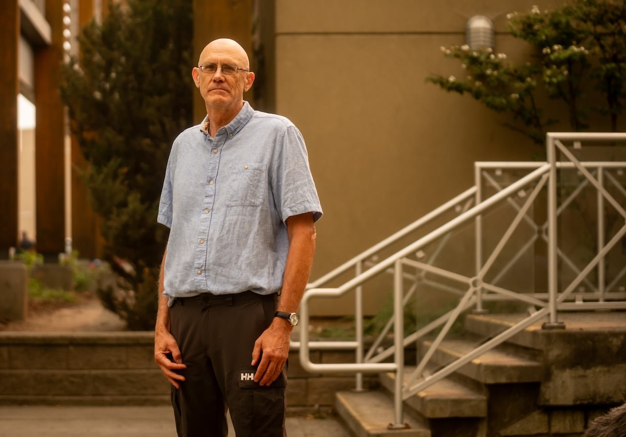 A bald man in a blue shirt amidst smoky conditions.