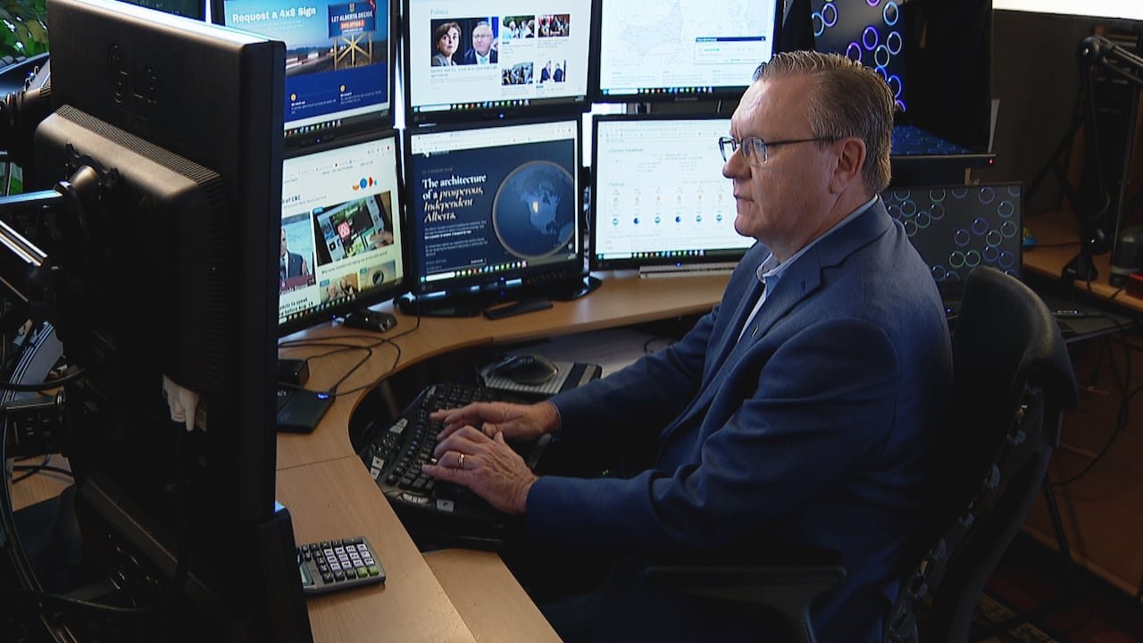 A man surrounded by computer screens.