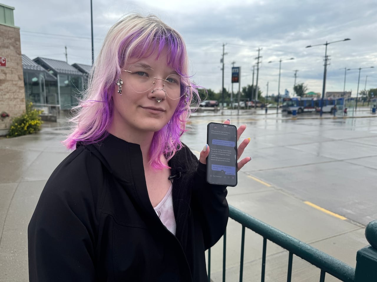 A woman stands with a cell phone beside her.